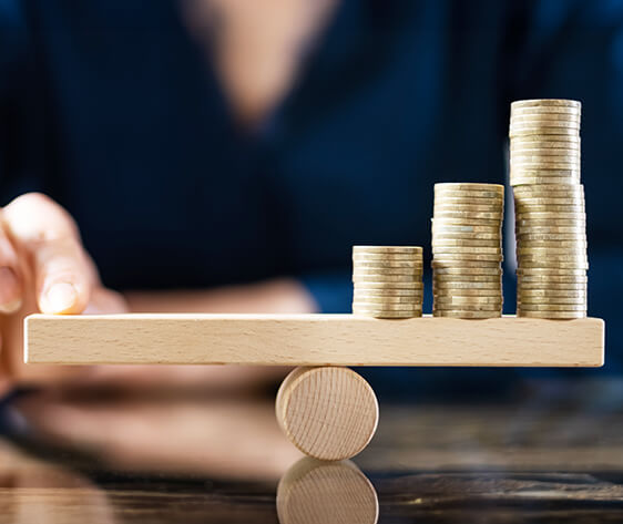Businessperson Balancing Stacked Coins On Seesaw