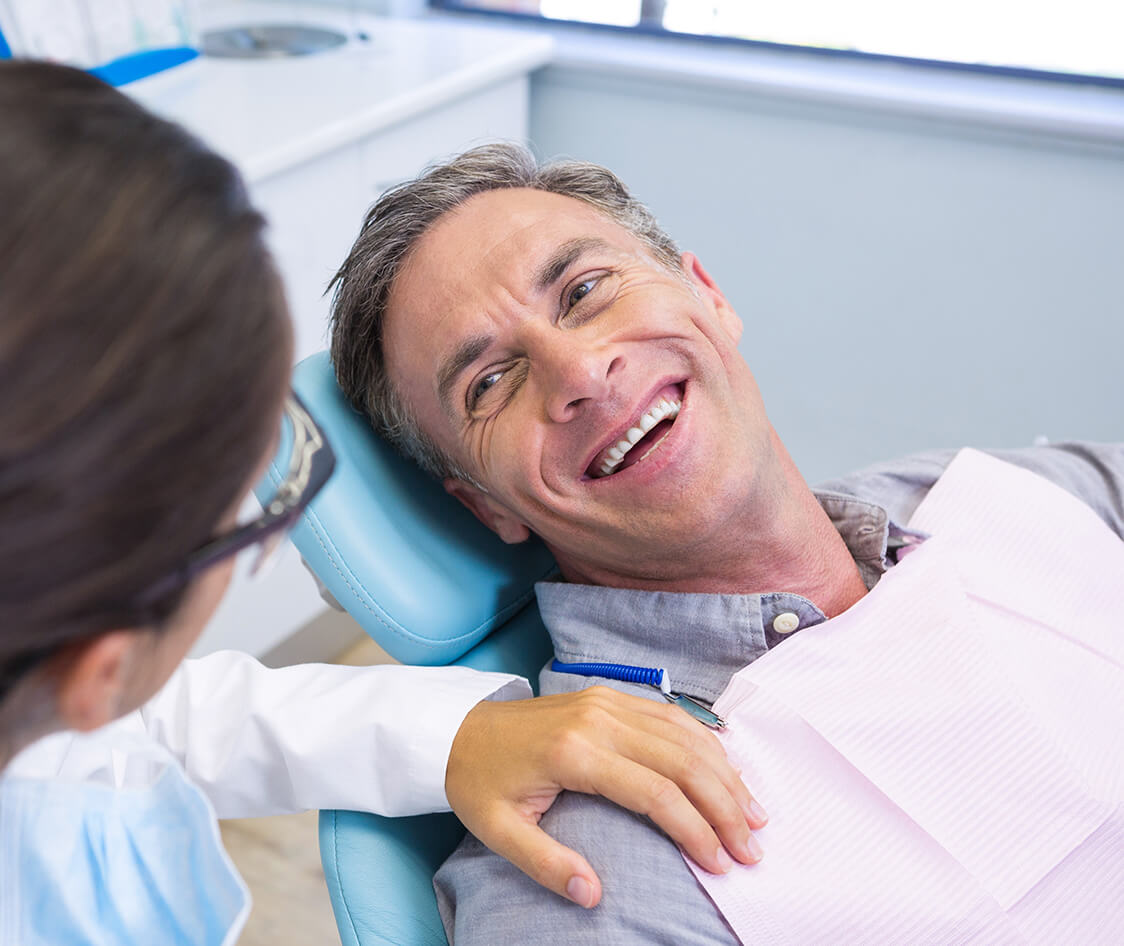 Patient sitting on chair while looking at dentist in medical